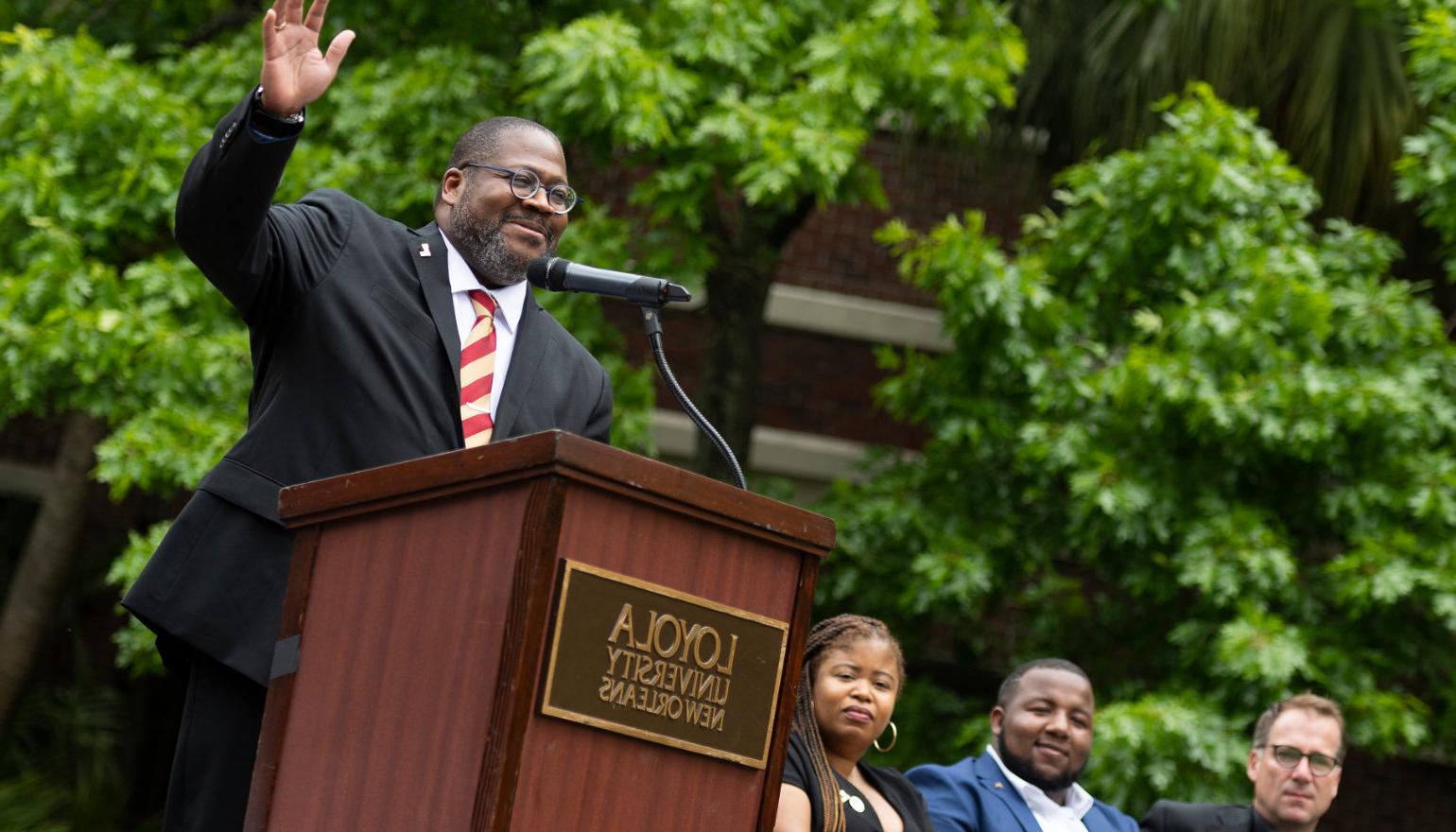 Xavier Cole raises his hand as he speaks at the podium